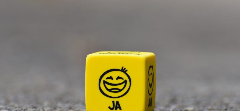 Close-up of a yellow dice featuring a smiley face emoticon symbolizing happiness and fun.