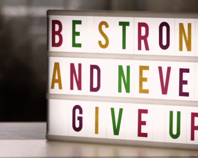 Inspirational lightbox displaying the motivational quote 'Be Strong and Never Give Up' indoors.