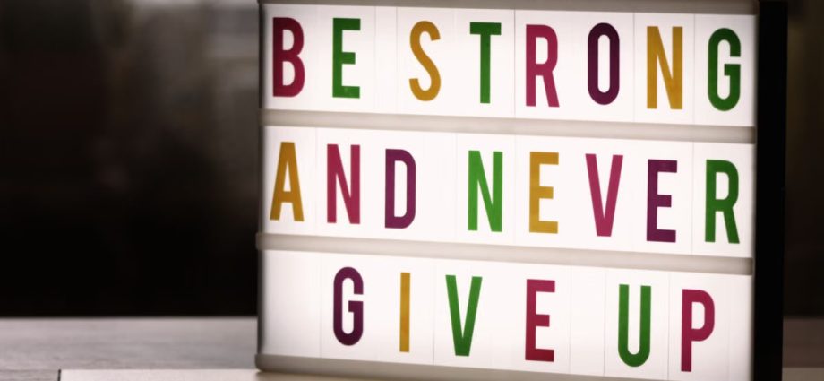 Inspirational lightbox displaying the motivational quote 'Be Strong and Never Give Up' indoors.